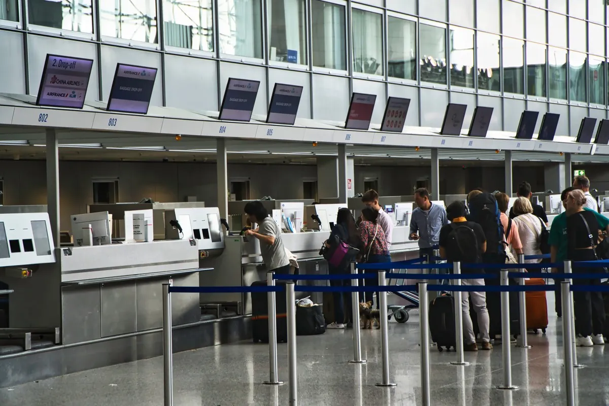 Kolejka do odprawy na lotnisku. Ludzie z bagażami czekają, by nadać walizki. To przypomina, co to jest turystyczny fundusz gwarancyjny.