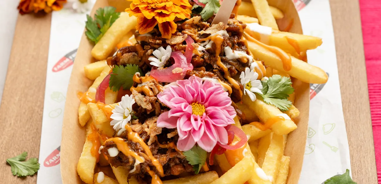 Idealne co do frytek na szybko: złociste frytki z mięsem, sosami, chrupiącą cebulką i jadalnymi kwiatami.