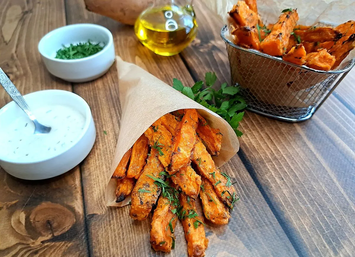 Jak przyprawić frytki z batatów? Podane z sosem i ziołami, wyglądają apetycznie.