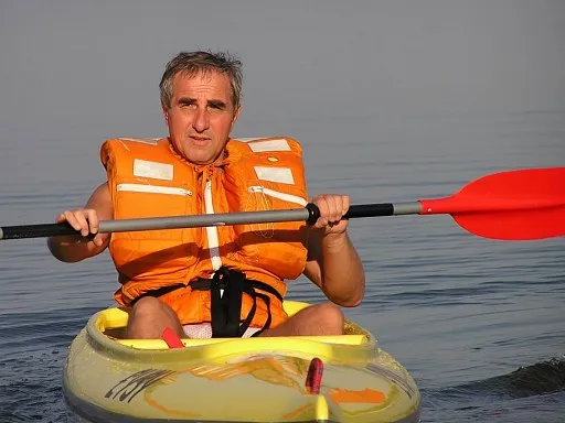 osoba na kajaku z kamizelką ratunkową i wiosłem