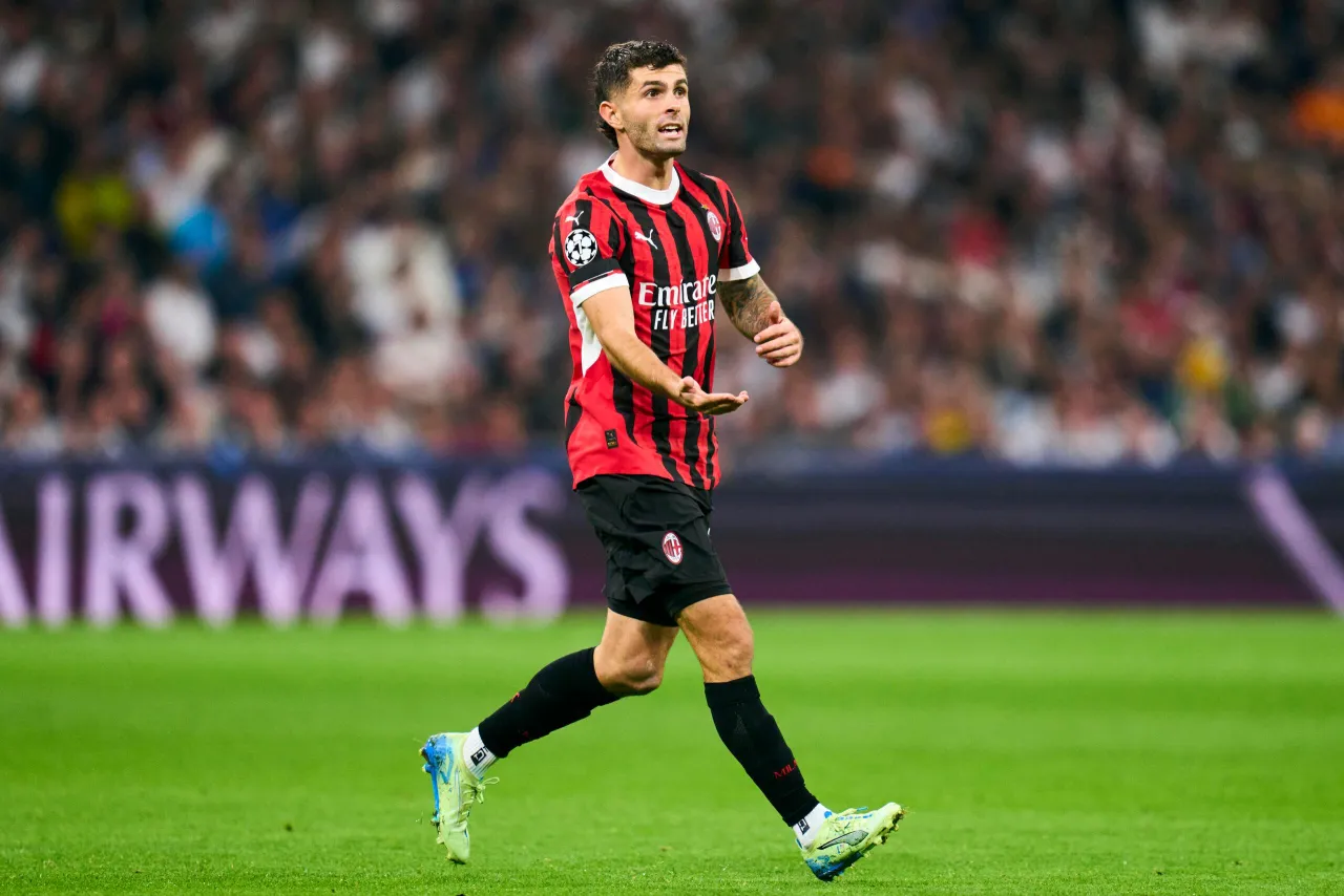 Piłkarz Milanu w czerwono-czarnej koszulce, z opaską Ligi Mistrzów, biegnie po boisku. Może to być kluczowy moment w klasyfikacji strzelców Ligi Mistrzów.