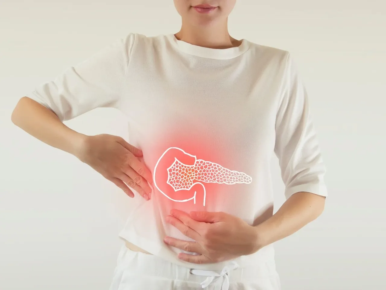 Kobieta trzyma się za brzuch, gdzie widoczny jest zarys trzustki z czerwonym podświetleniem, sugerującym zapalenie trzustki objawy.