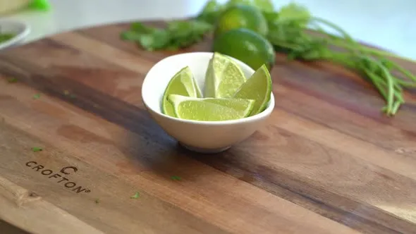 Frische Limetten und Limettenhälften auf einem Schneidebrett