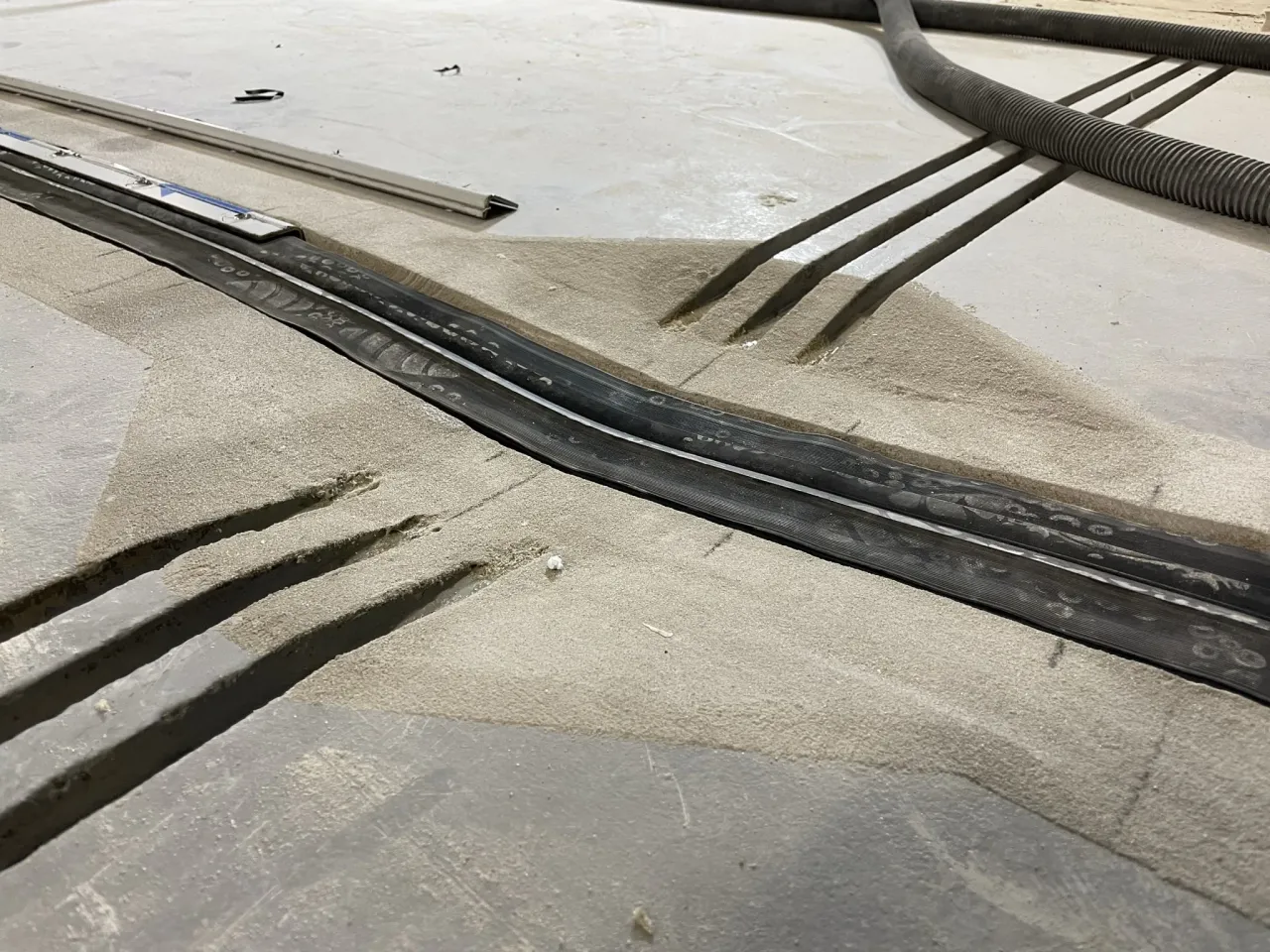 Przygotowanie podłoża do wykonania betonowego podjazdu: wycięte rowki, piasek i gumowe profile.