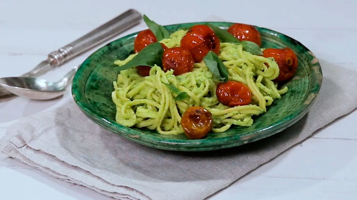 pasta integral con pesto de aguacate y tomates cherry en un bol blanco