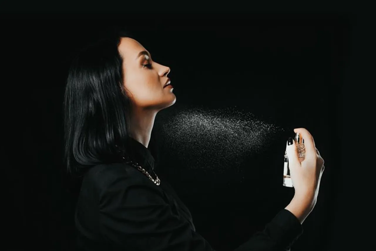 kobieta aplikująca perfumy na szyję