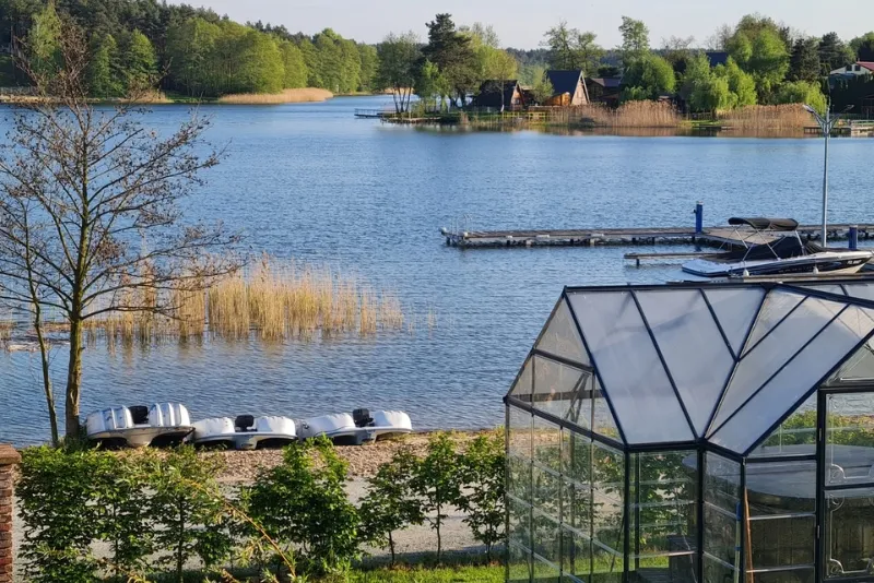 Wędkarz nad jeziorem w Wielkopolsce z domkiem w tle