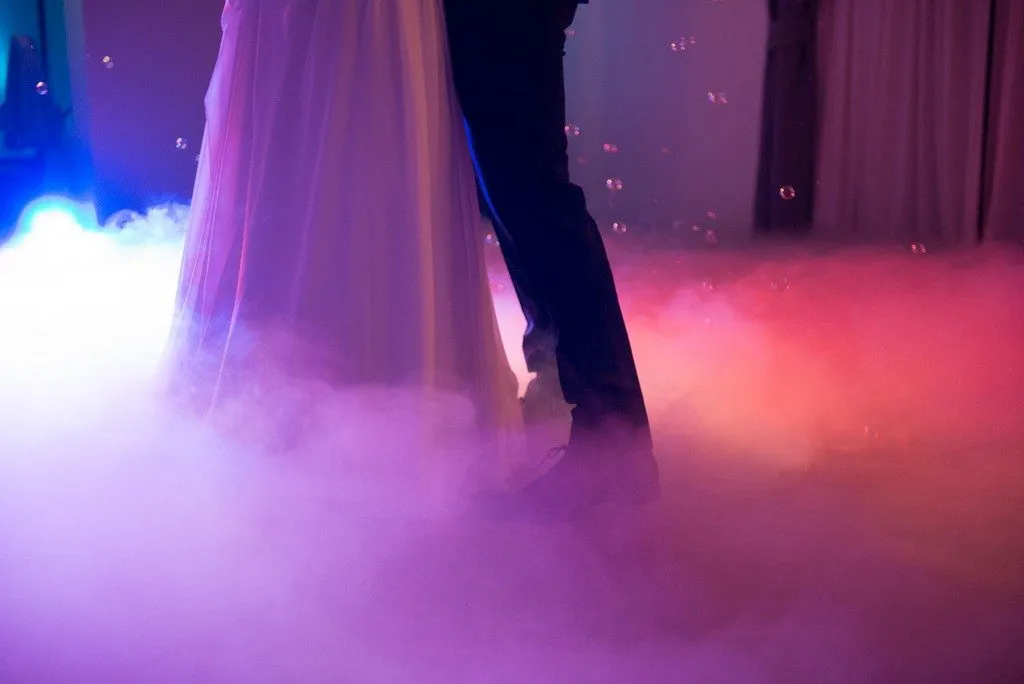Młodzi ludzie tańczący przy ciężkim dymie i świetle laserowym na imprezie