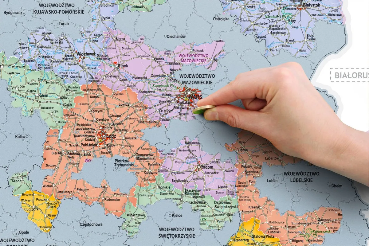 Dłoń z monetą wskazuje na mapę Polski, szukając miejsca, gdzie kupić zdrapki lotto.