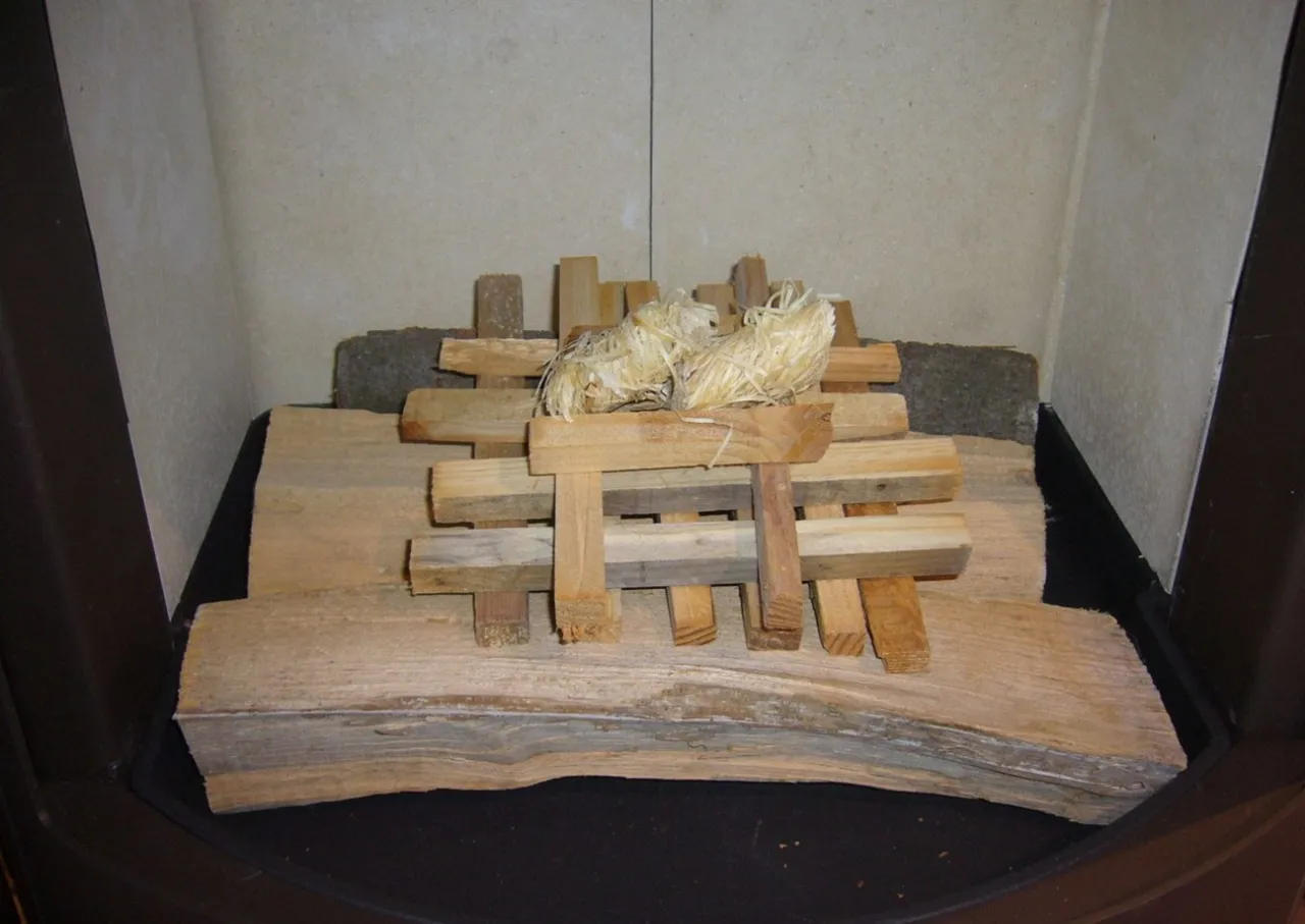 Ułożone drewno i słoma w kominku, gotowe do rozpalenia. Oto jak rozpalić w kominku bez podpałki, używając naturalnych materiałów.