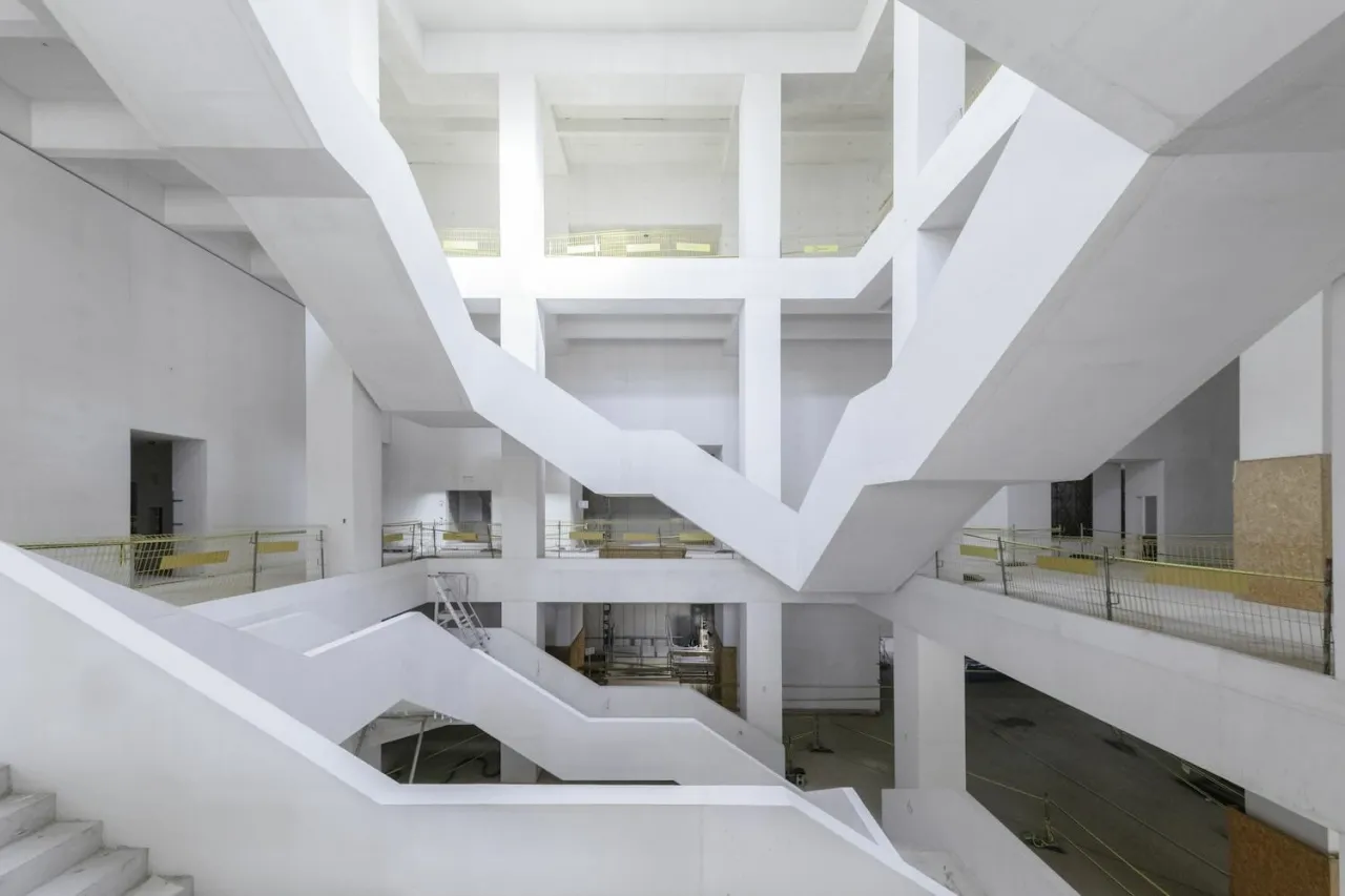 Wnętrze muzeum sztuki nowoczesnej Warszawa projekt: białe, geometryczne schody i belki tworzą labirynt.