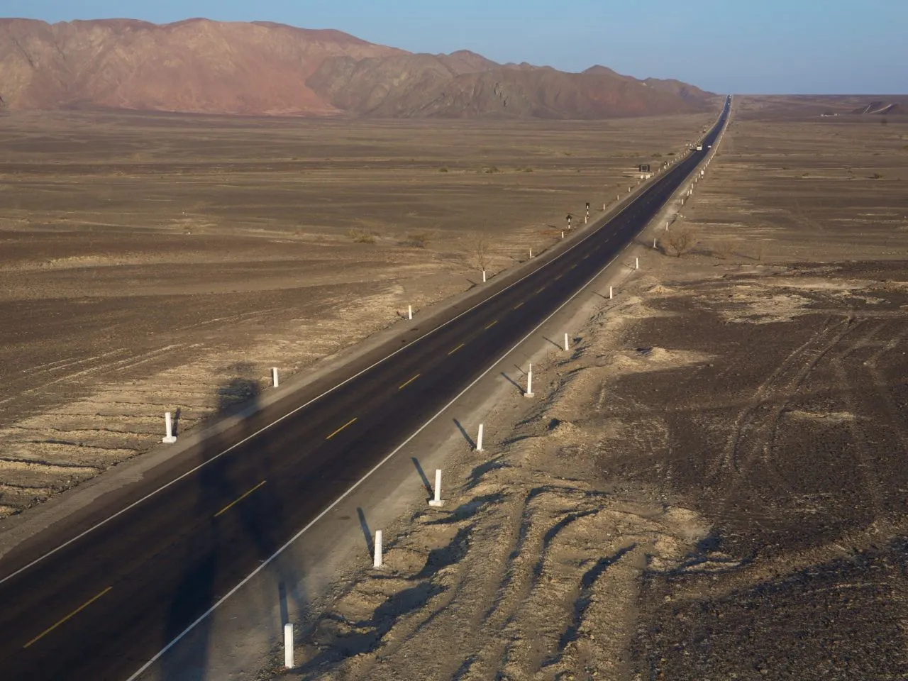Pustynny krajobraz z prostą drogą, kt&oacute;ra wydaje się być najdłuższą autostradą na świecie.