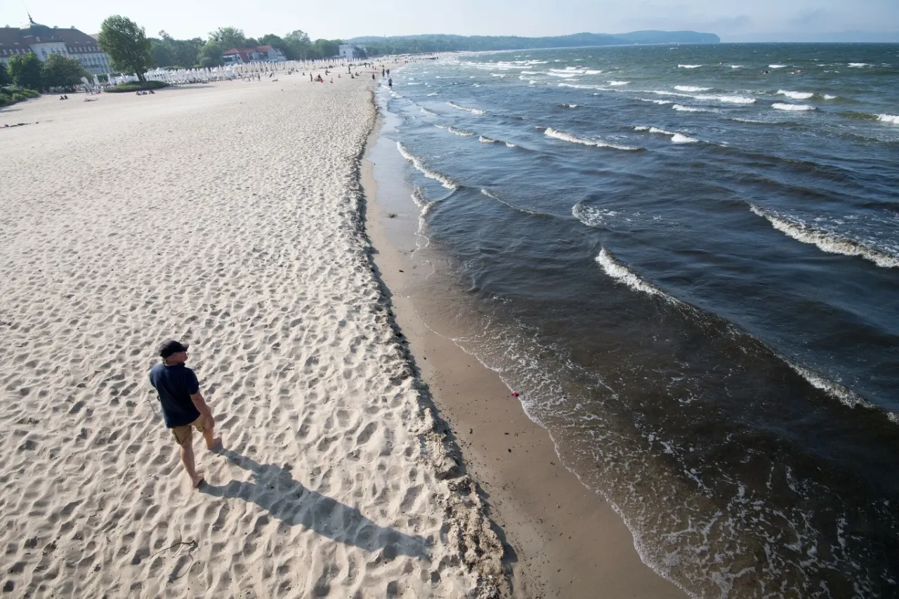 Mężczyzna spaceruje po piaszczystej plaży, ciesząc się świeżym powietrzem i falami. Idealne miejsce, kiedy jod nad morzem.
