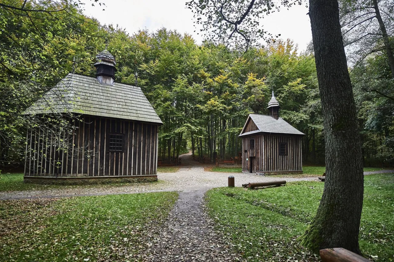 Dwie drewniane kapliczki w rezerwacie przyrody Las Łagiewnicki, otoczone jesiennym lasem.