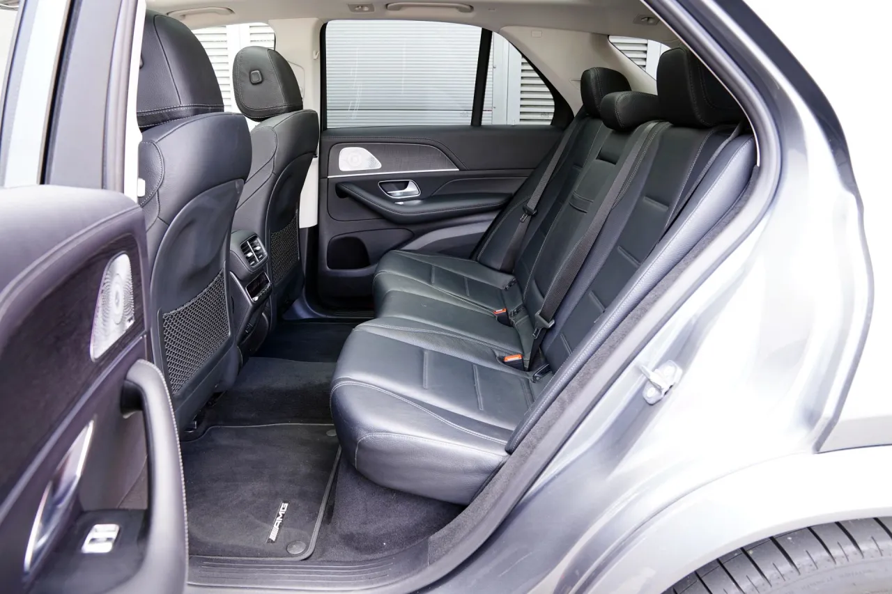 Wnętrze luksusowego Mercedesa GLE 300 d. Skórzane fotele, dyskretne oświetlenie i dywaniki z logo AMG tworzą komfortową przestrzeń.