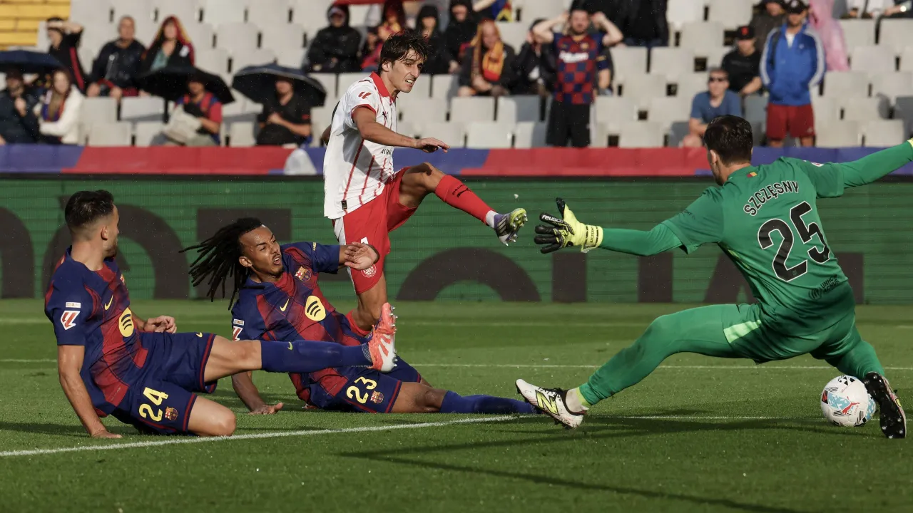 Piłkarze walczą o piłkę, a bramkarz Wojciech Szczęsny wzrostem przewyższa rywali, broniąc bramkę.