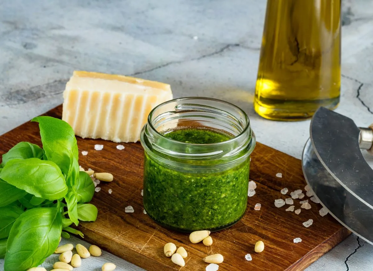 Słoiczek pesto z bazylii, świeże liście bazylii, orzeszki piniowe, kawałek parmezanu i oliwa - idealne składniki, by pokazać, co zrobic z lisci bazylii.
