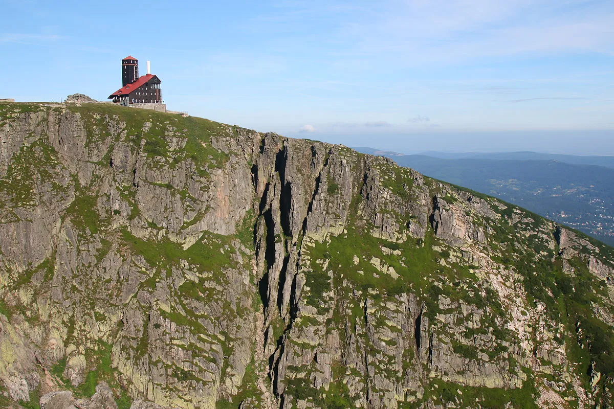 Schronisko pod Łabskim Szczytem dumnie stoi na skalistym zboczu, górując nad zielonymi dolinami.