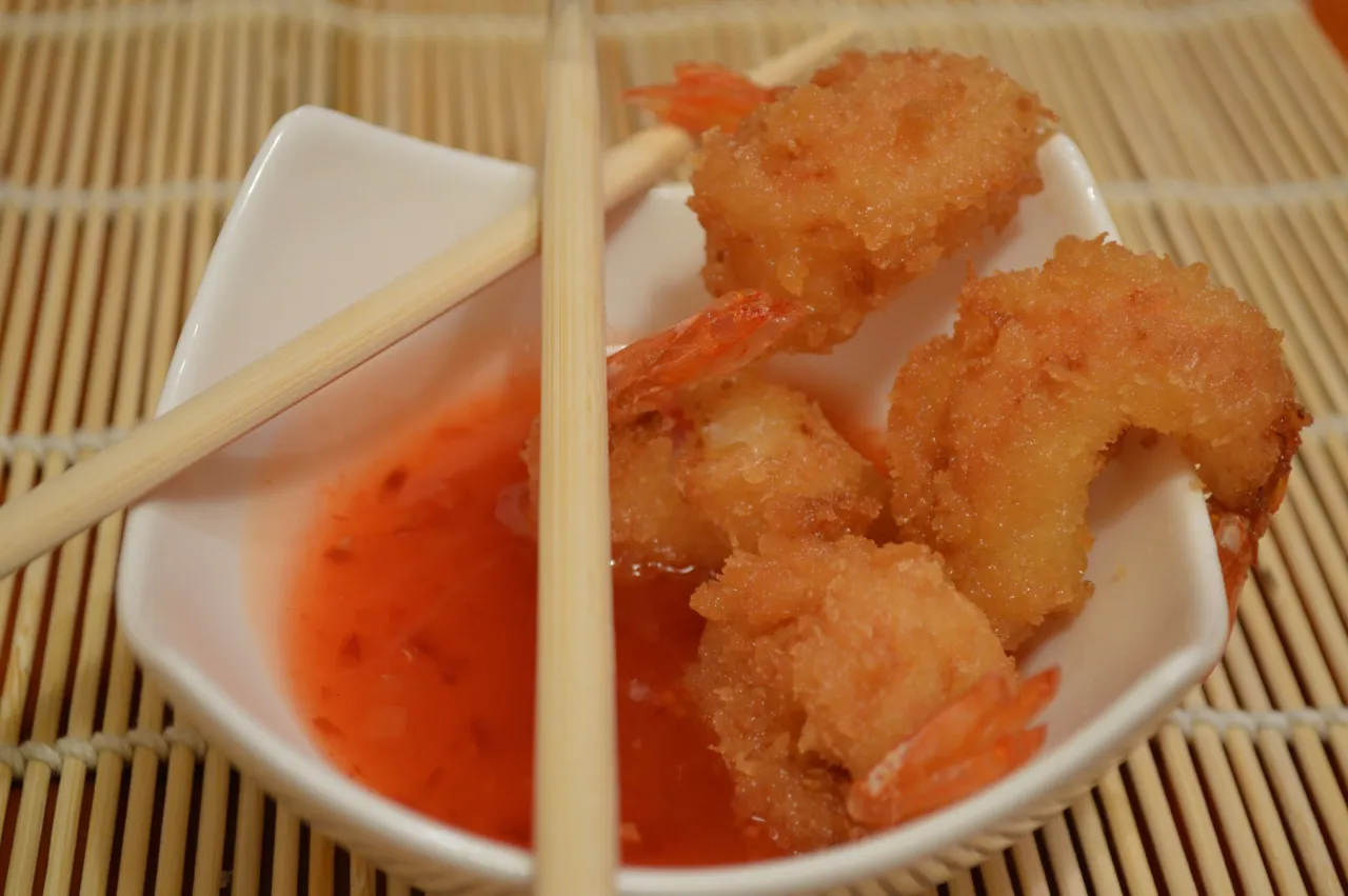 Chrupiące krewetki w panko, zanurzone w słodko-pikantnym sosie, czekają na pałeczki.