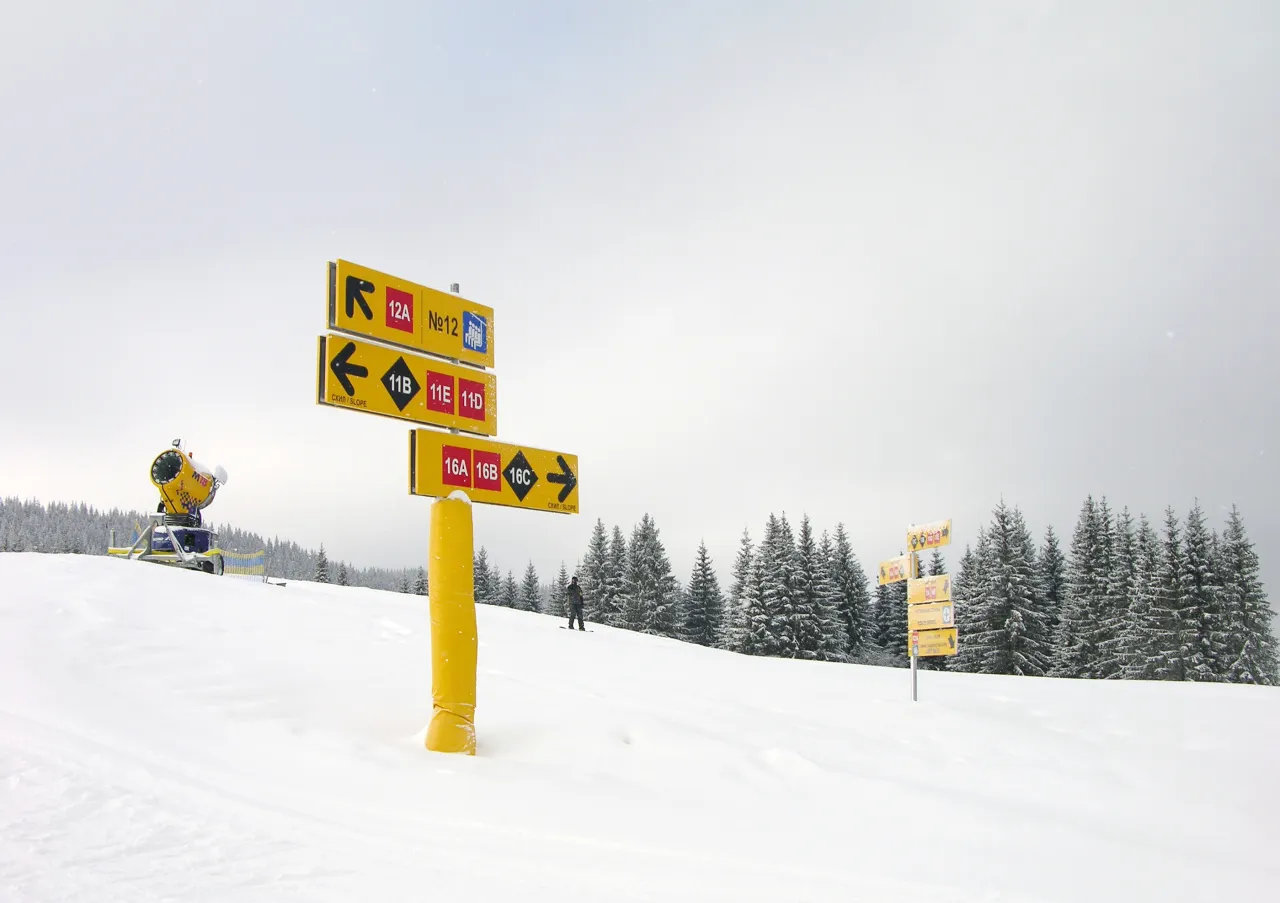 Znakowanie tras narciarskich w Polsce. Śnieg, drzewa i maszyna do naśnieżania.