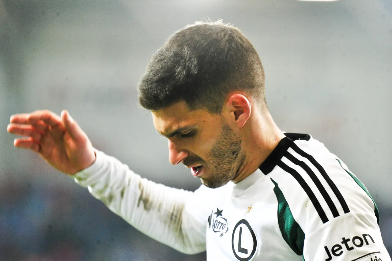 Piłkarz w białej koszulce z czarnymi pasami, zastanawiający się, ile zarabia przeciętny piłkarz ekstraklasy.