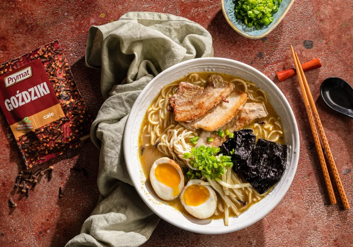 Jak ugotować ramen? Aromatyczny bulion, makaron, jajko, mięso i nori. Obok paczka goździków Prymat.