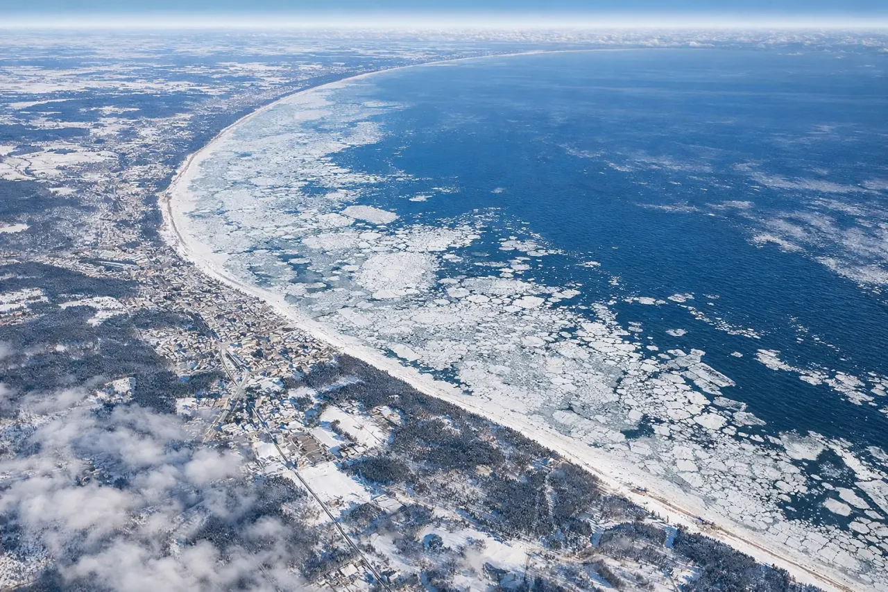 Zima na wybrzeżu. Widać, czy morze bałtyckie zamarza, pokryte lodem i śniegiem, z miasteczkiem w tle.
