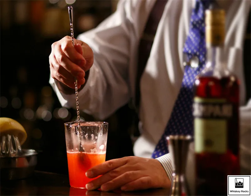 barman profesjonalnie degustujący koktajl z łyżeczki barmańskiej