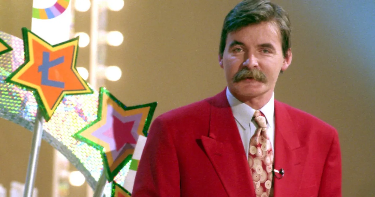 Kto prowadził Koło Fortuny w latach 90.? To on, w czerwonym garniturze, z charakterystycznym wąsem, obok gwiazdek z literą 