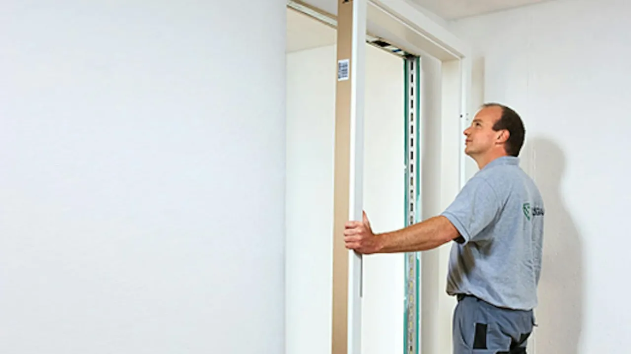 Mężczyzna montuje futrynę drzwi. Instrukcja jak zamontować drzwi wewnętrzne krok po kroku.