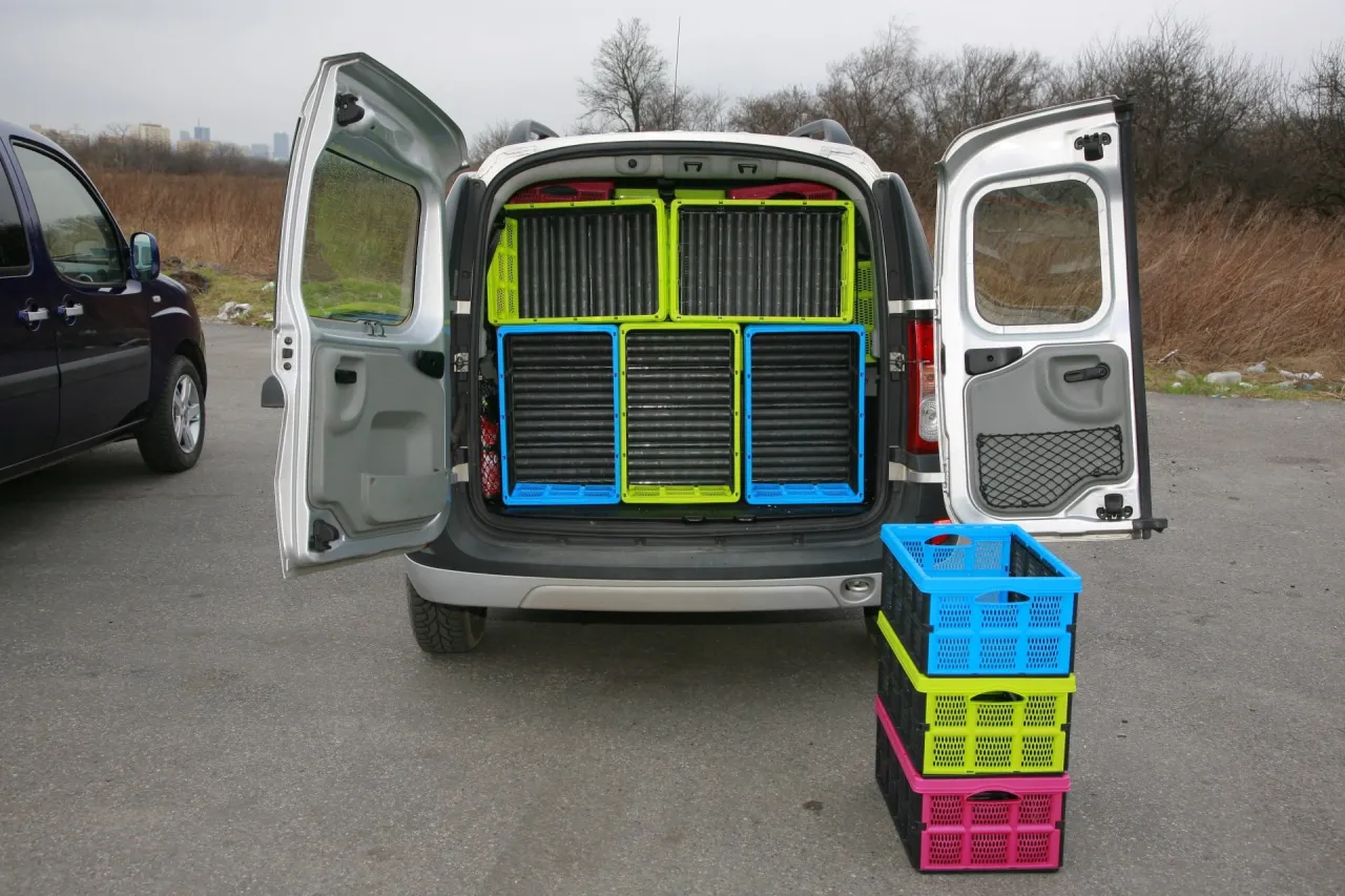 Taki bus do 10 tys. z otwartym tyłem, pełnym zielonych i niebieskich skrzynek. Obok stos kolorowych pojemnik&oacute;w.