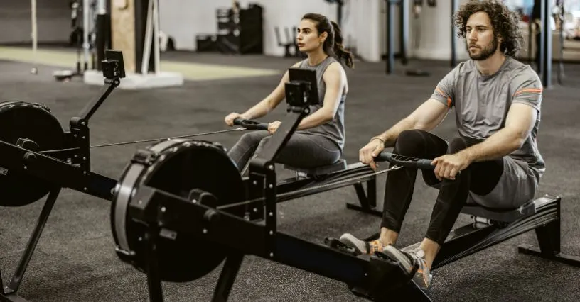 osoba ćwicząca na wioślarzu w siłowni