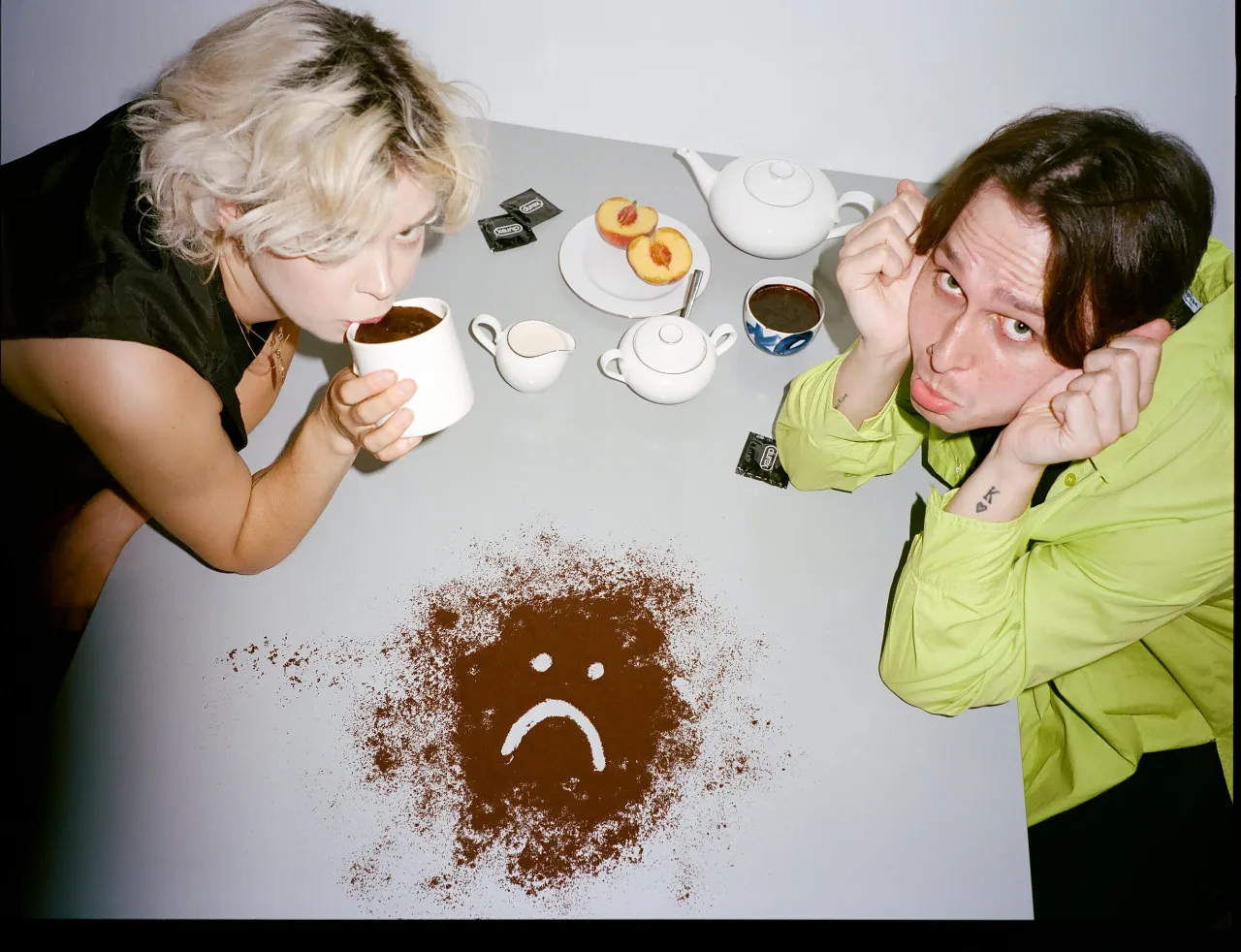 Para, kawa i smutna buźka z kawy. Czy wytrysk w prezerwatywie jest bezpieczny? Dwa opakowania prezerwatyw Durex leżą obok.