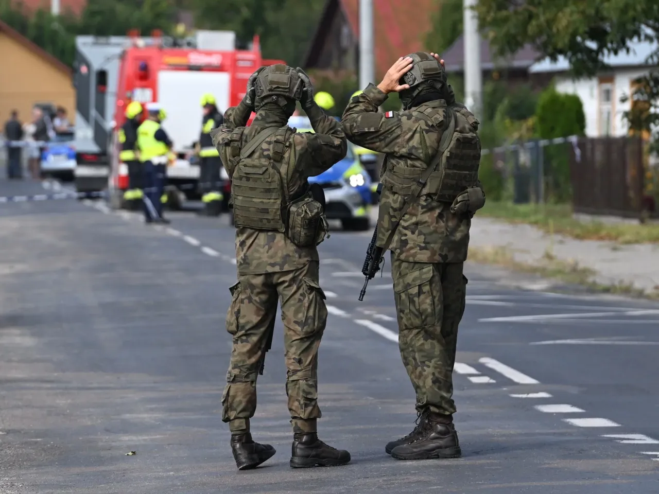 Żołnierze w pełnym rynsztunku, gotowi na nieprzewidziane zdarzenia, przypominają o potrzebie ubezpieczenia na wypadek wojny. W tle wóz strażacki i policyjny.