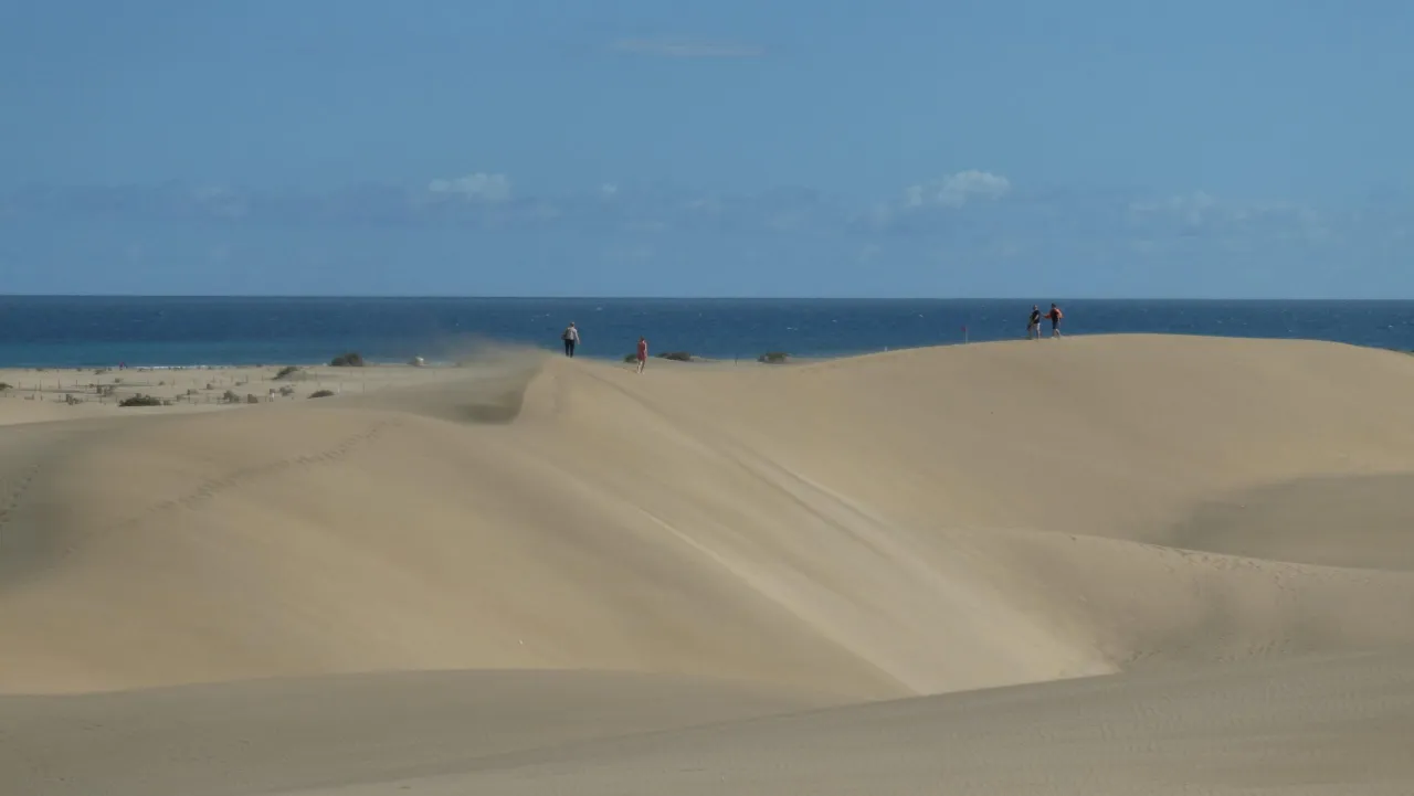 Plaża na Wyspach Kanaryjskich z turystami, symbolizująca europejski standard wypoczynku