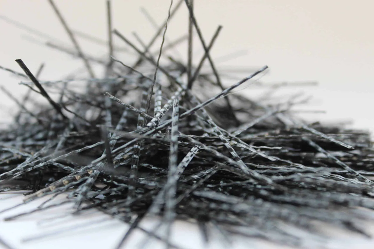 Stos cienkich, czarnych włókien do betonu, które zwiększają jego wytrzymałość.