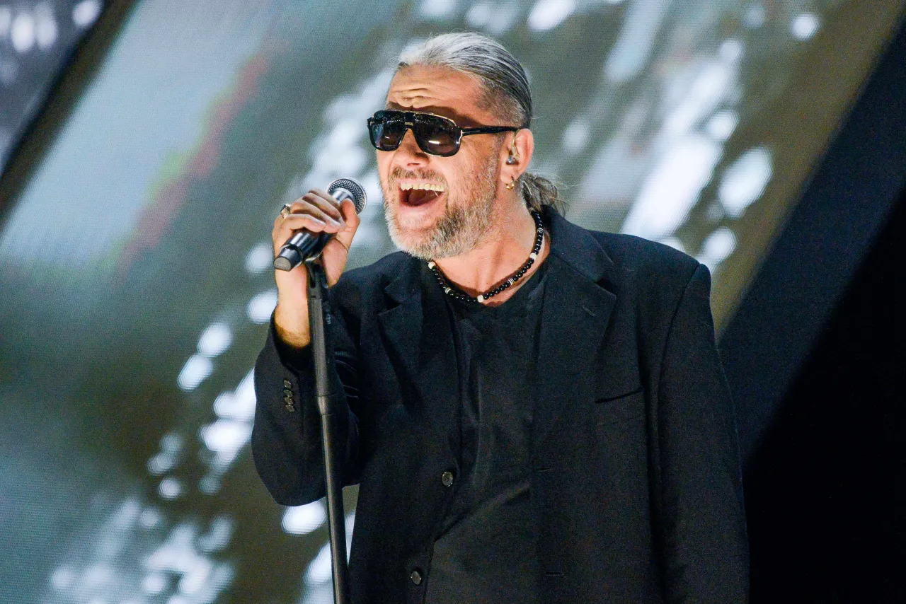 Charyzmatyczny wokalista z siwymi włosami i okularami przeciwsłonecznymi śpiewa do mikrofonu. Czy to on śpiewa 