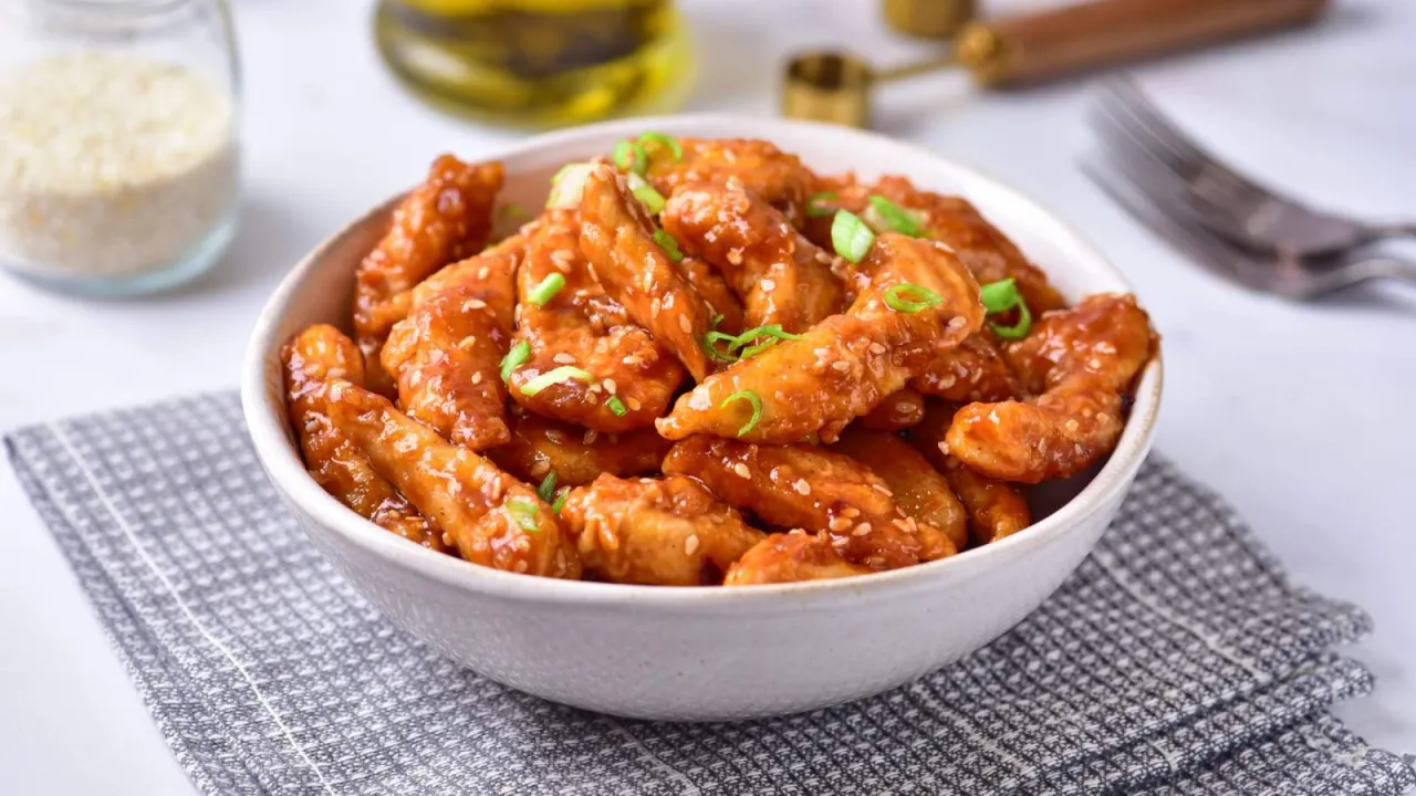 Chrupiące kawałki kurczaka w sosie sojowym, posypane sezamem i szczypiorkiem. Idealne jako danie główne lub przekąska.