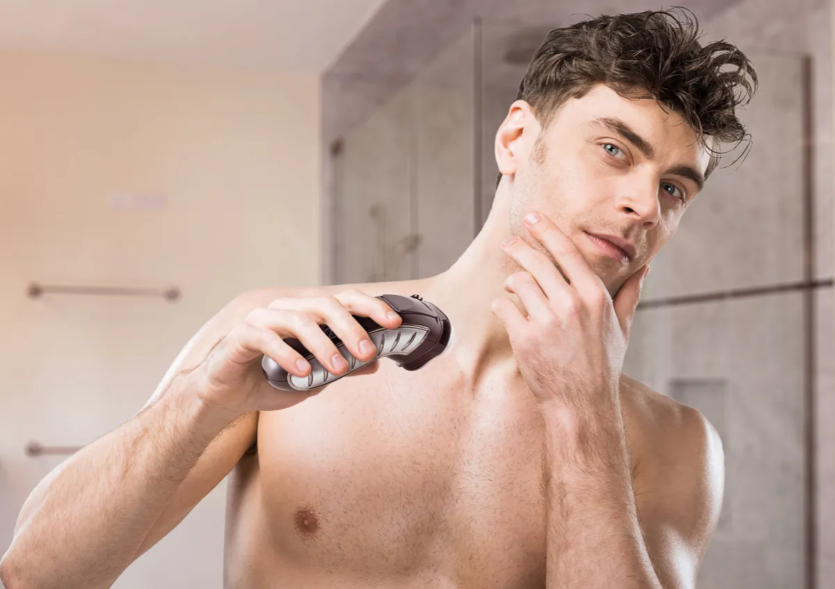 Mężczyzna przygotowujący skórę do golenia maszynką elektryczną