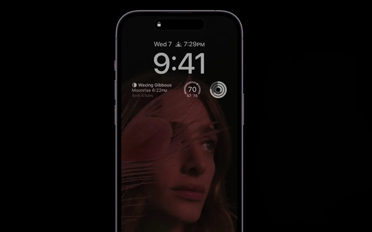 Ekran blokady iPhone 14 z datą, godziną i zdjęciem kobiety. Czy oplaca sie kupic iPhone 14?