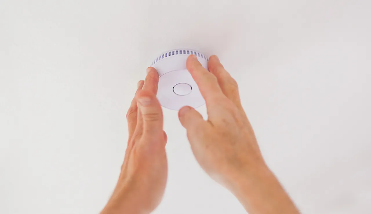 Ręce montują czujnik czadu i gazu na suficie. Dowiedz się, gdzie zamontować czujnik czadu i gazu dla bezpieczeństwa.