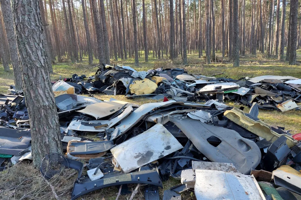 Nielegalne wysypisko śmieci w lesie, porzucone części samochodowe