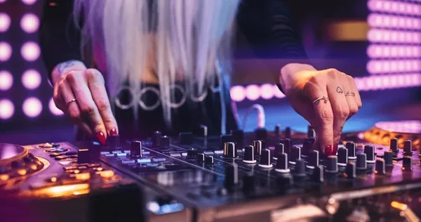 DJ na konsoli miksujący muzykę z publicznością w tle