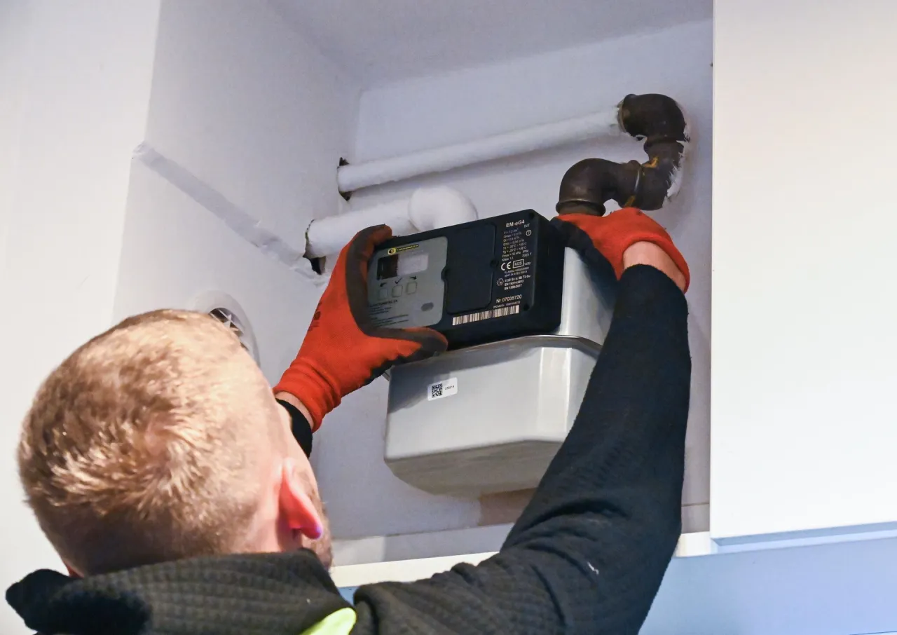 Technik w rękawiczkach montuje nowy gazomierz. Szybka wymiana gazomierza to klucz do sprawnego funkcjonowania instalacji.