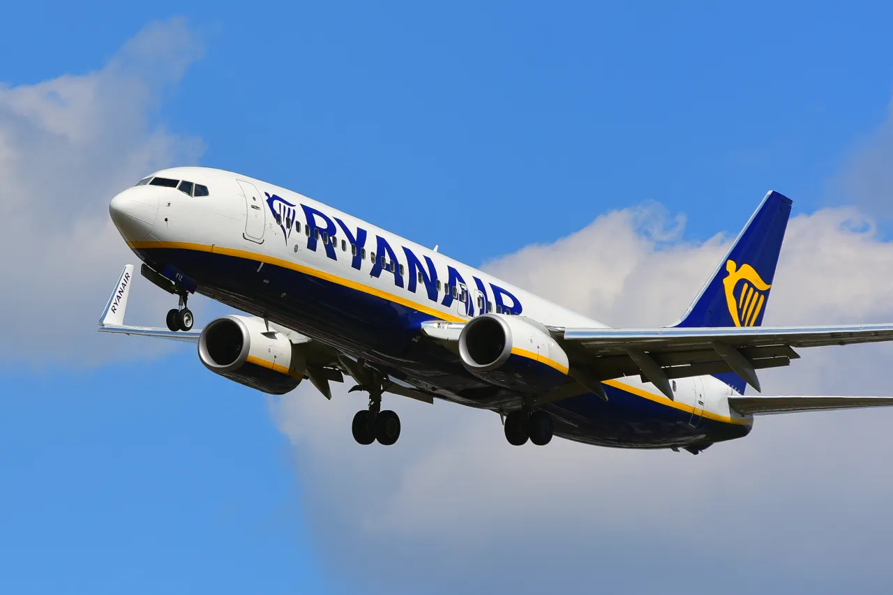 Samolot Ryanair wznosi się na tle błękitnego nieba z chmurami. Zastanawiasz się, ile trwa lot z Polski do Jordanii?