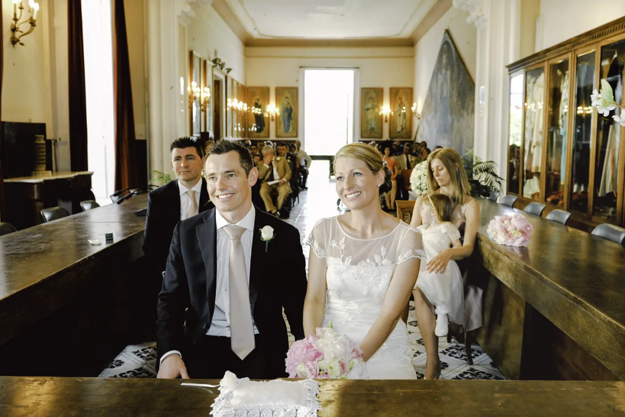 Para młoda i jej świadek, czy na ślubie cywilnym są świadkowie? W tle goście i dekoracje.