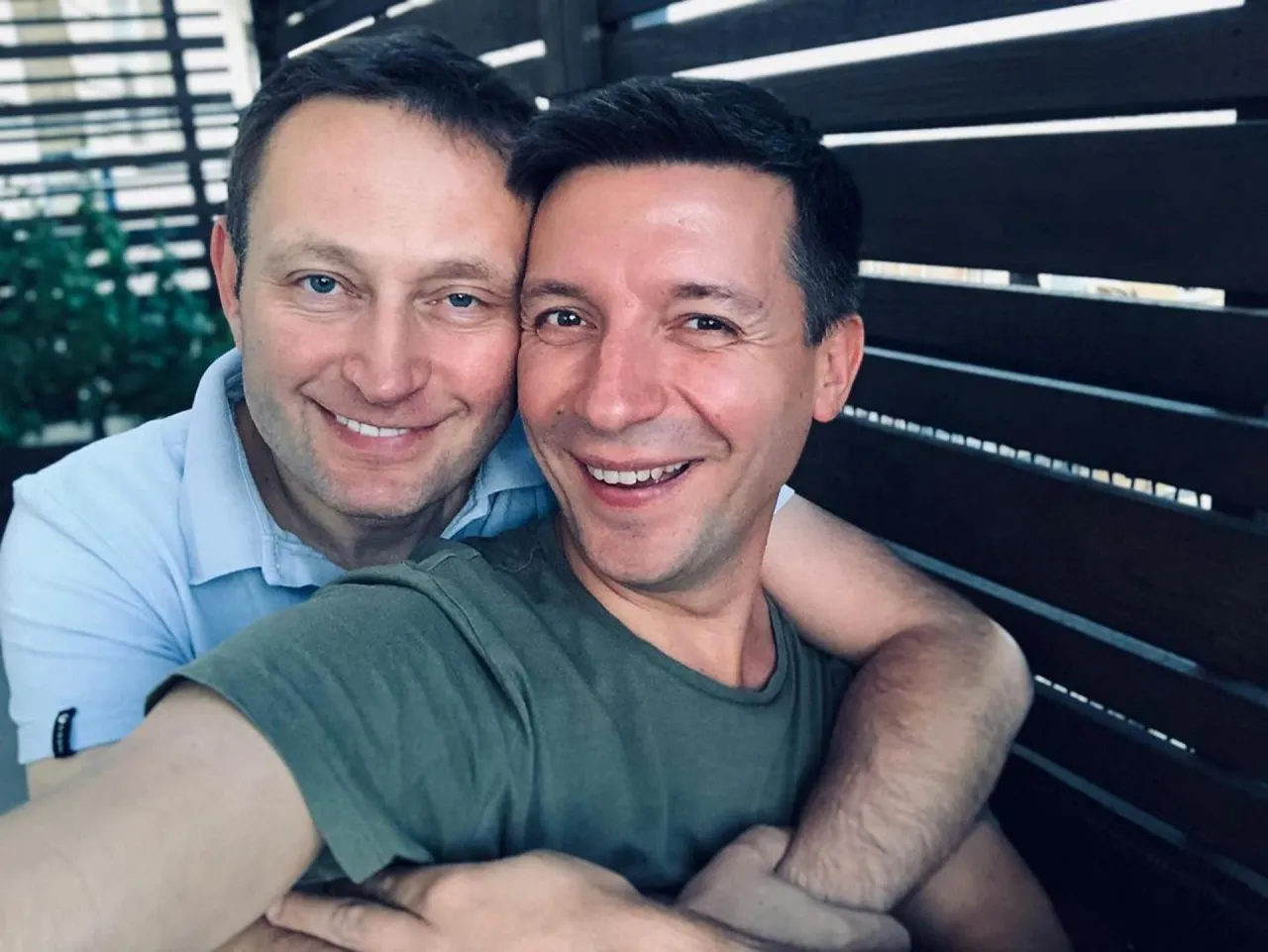 Uśmiechnięci mężczyźni, jeden w jasnej koszuli, drugi w zielonej koszulce. To Michał Cessanis i jego żona, szczęśliwi razem.