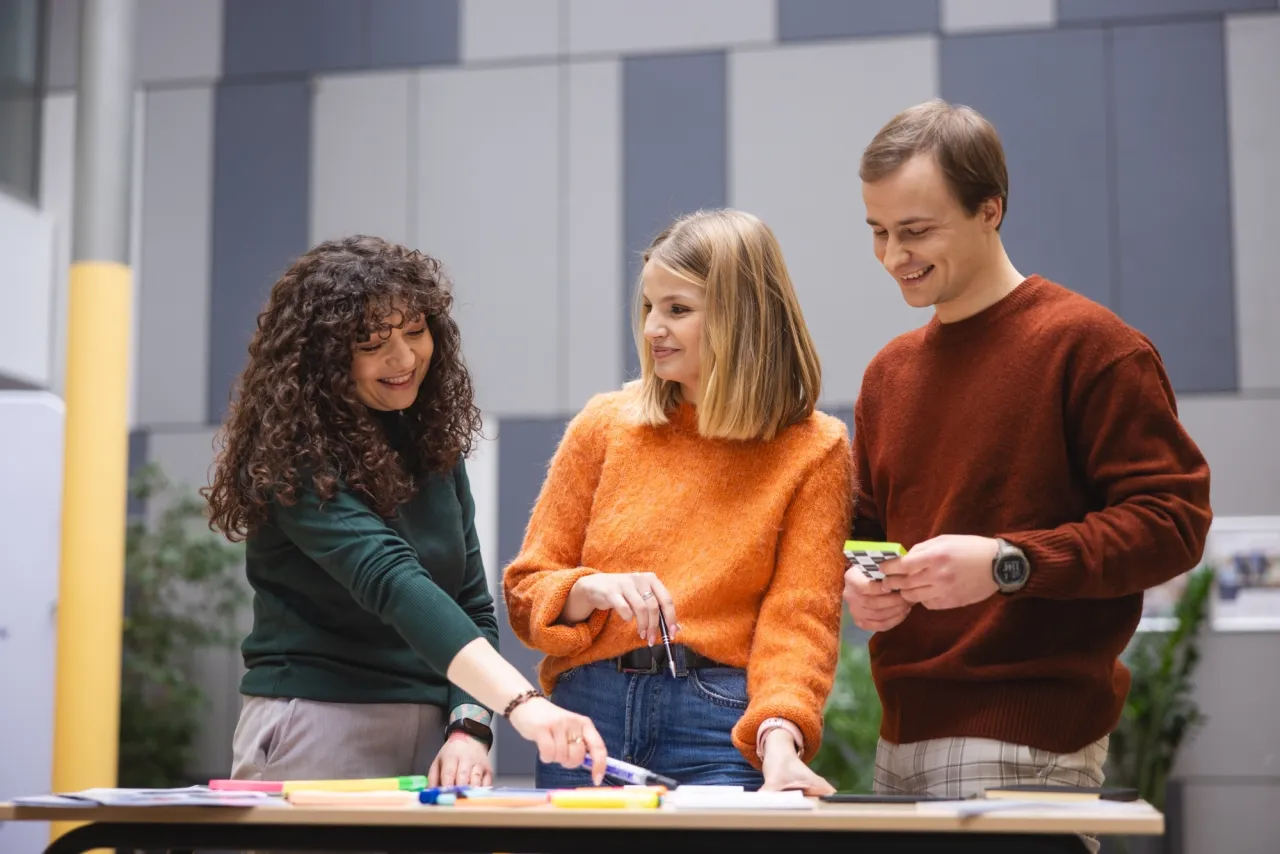 Trzy osoby dyskutują nad materiałami, planując, jak zostać terapeutą integracji sensorycznej.