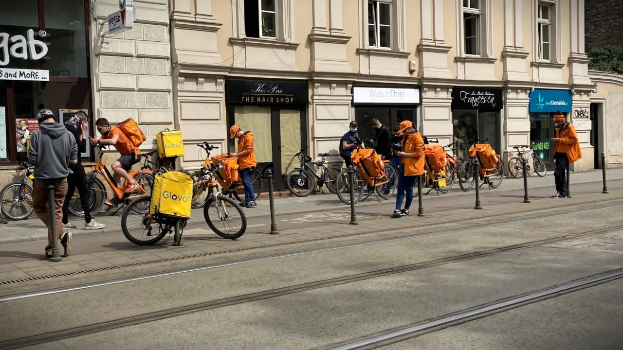 Kurier Glovo na rowerze dostarczający jedzenie w dużym mieście