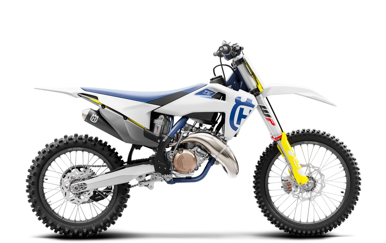 Motocykl Husqvarna TC 125 w białej odsłonie z niebieskimi i żółtymi akcentami, gotowy do podboju toru.